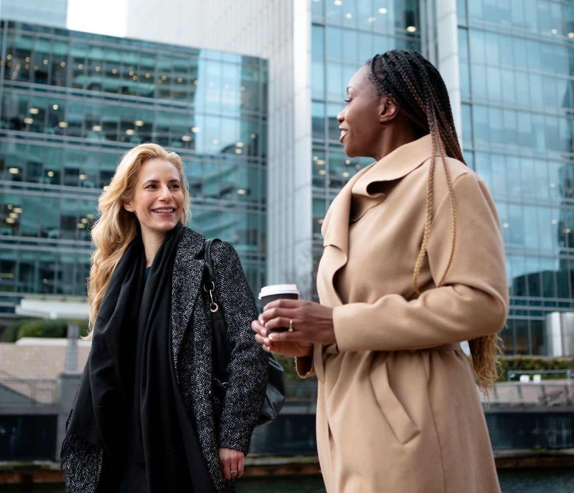 Two women are standing next to each other in front of a building.