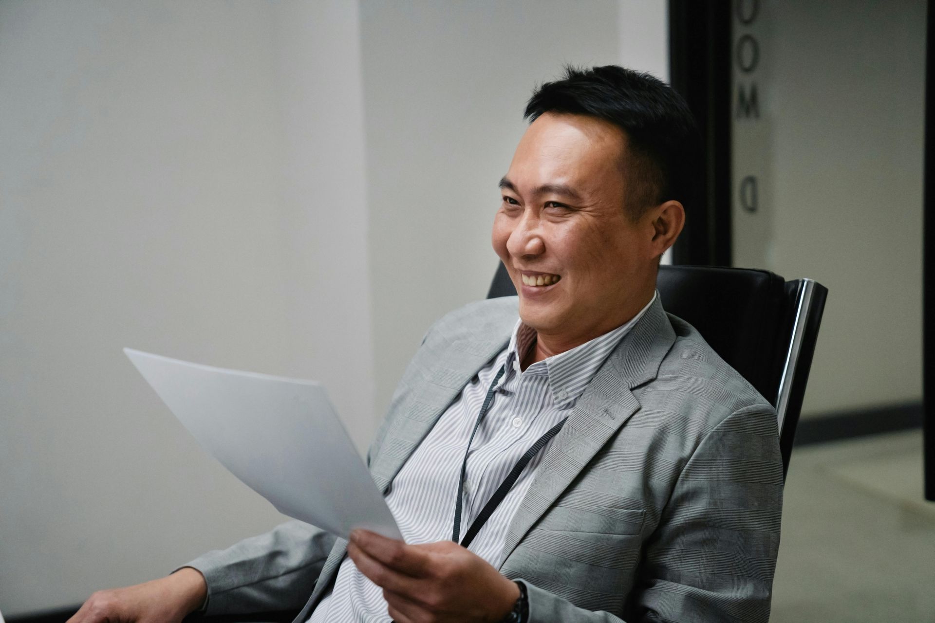 A man in a suit is sitting in a chair holding a piece of paper.