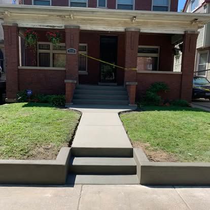 Brick house with porch, steps, and new concrete sidewalk. Green grass surrounds. Brick house with porch, steps, and new concrete sidewalk. Green grass surrounds.