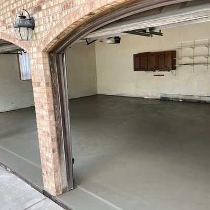 Gray concrete floor inside a garage with brick archway and cabinets on the wall. Gray concrete floor inside a garage with brick archway and cabinets on the wall.
