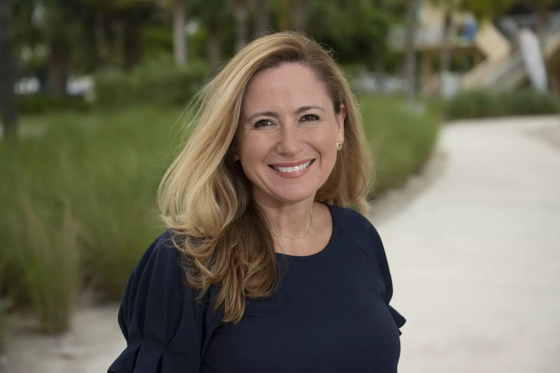 A woman is smiling for the camera while standing on a path.