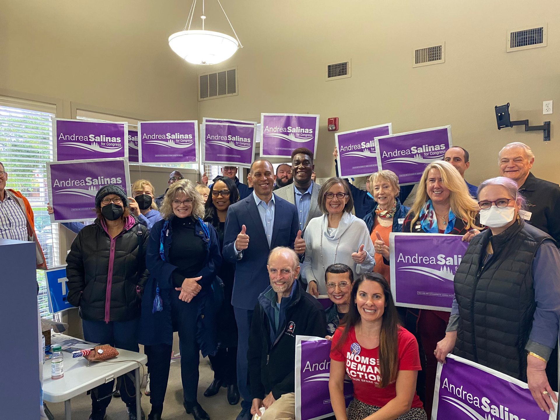 A group of people are standing in a room holding purple signs.