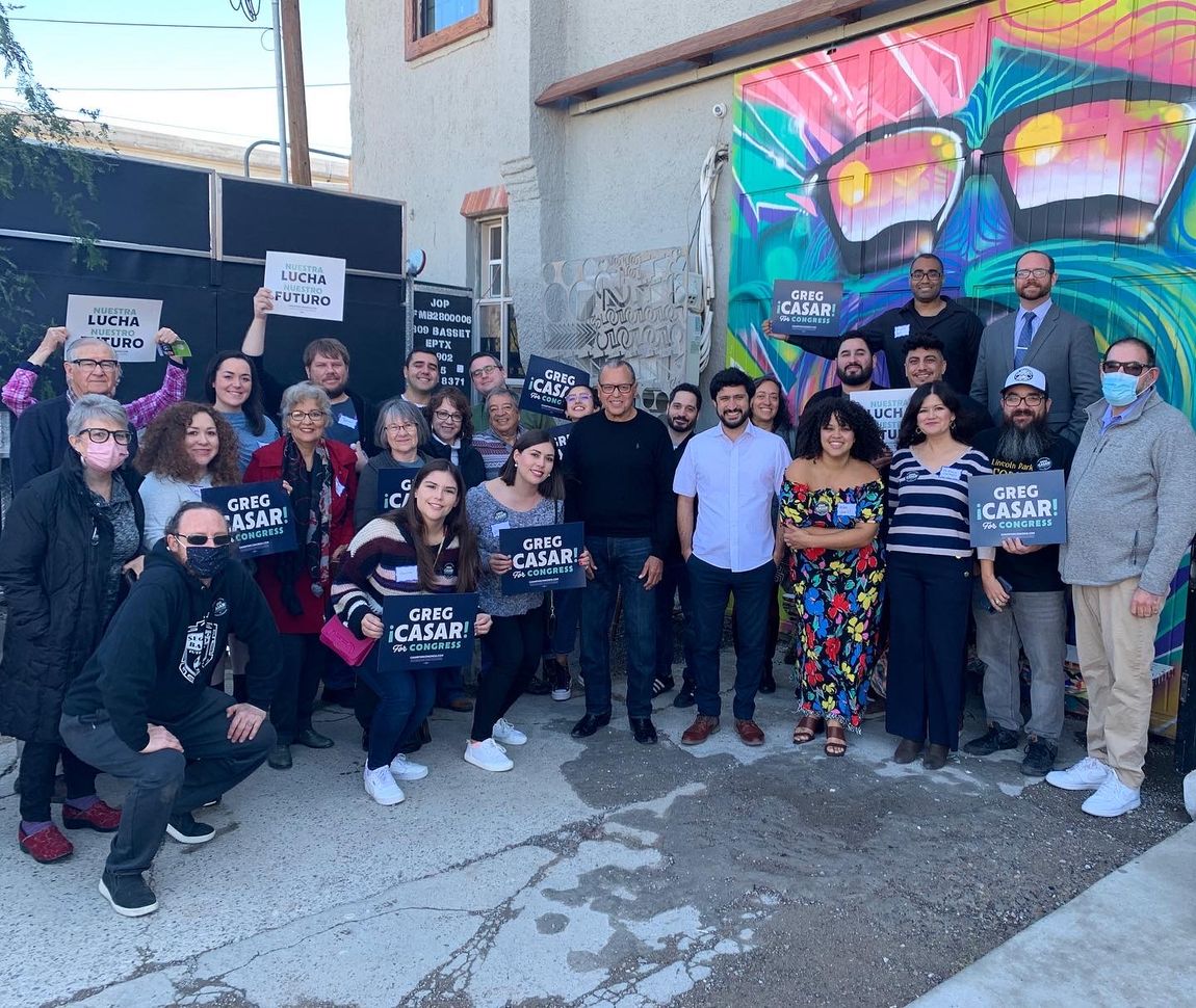 A group of people are posing for a picture in front of a mural.