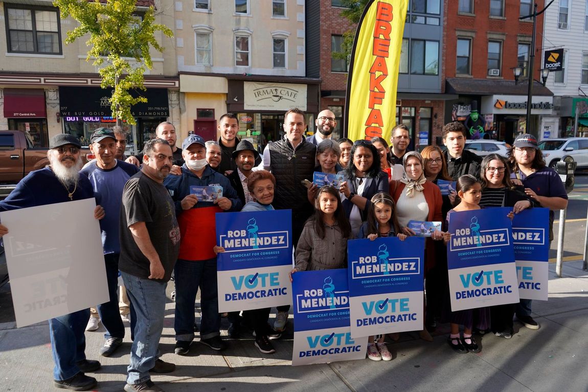 A group of people standing on a sidewalk holding signs that say vote