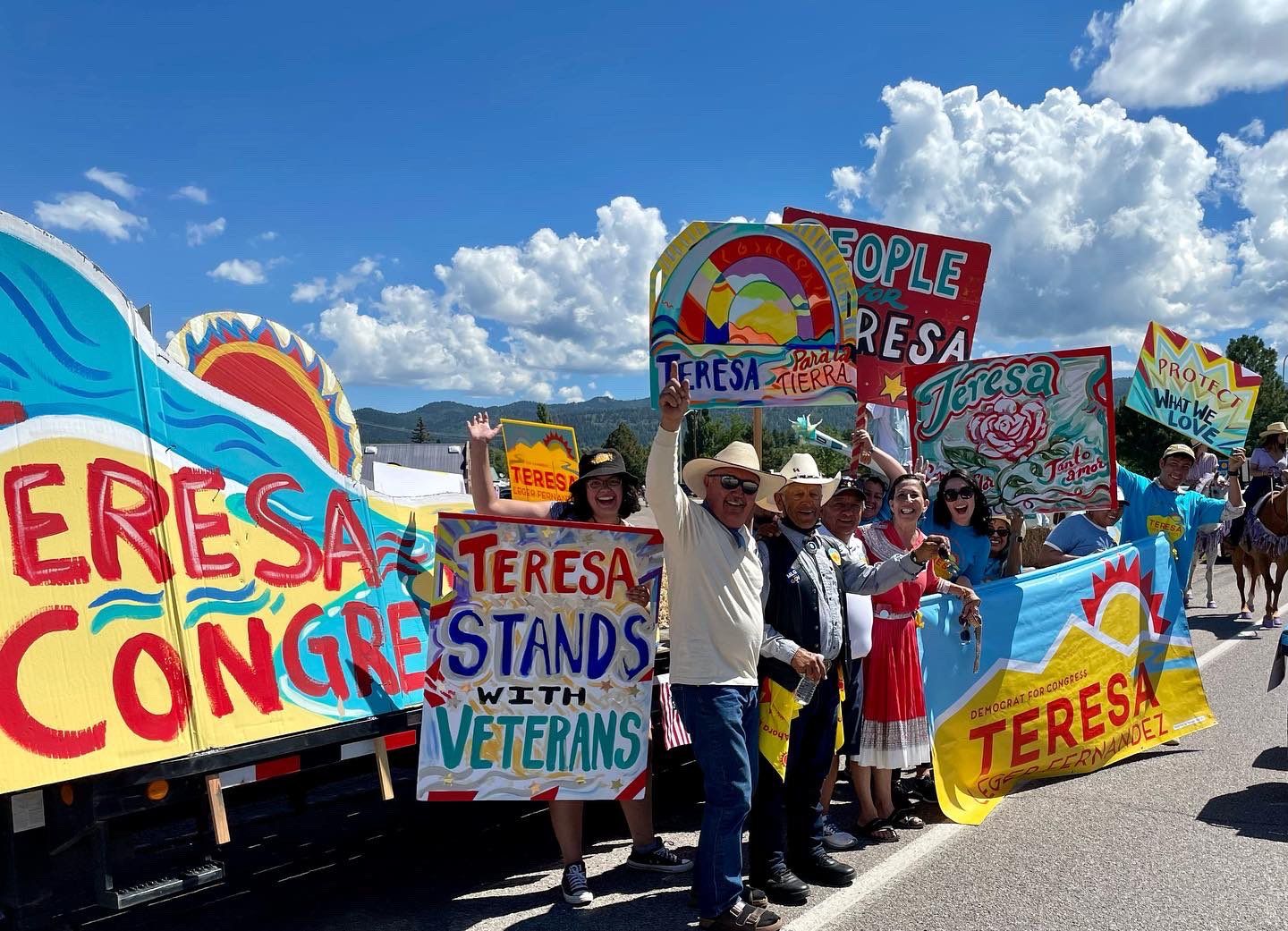A group of people are standing in front of a truck holding signs.