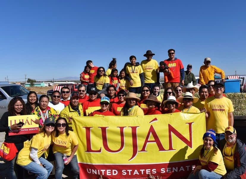 A group of people standing in front of a lujan sign
