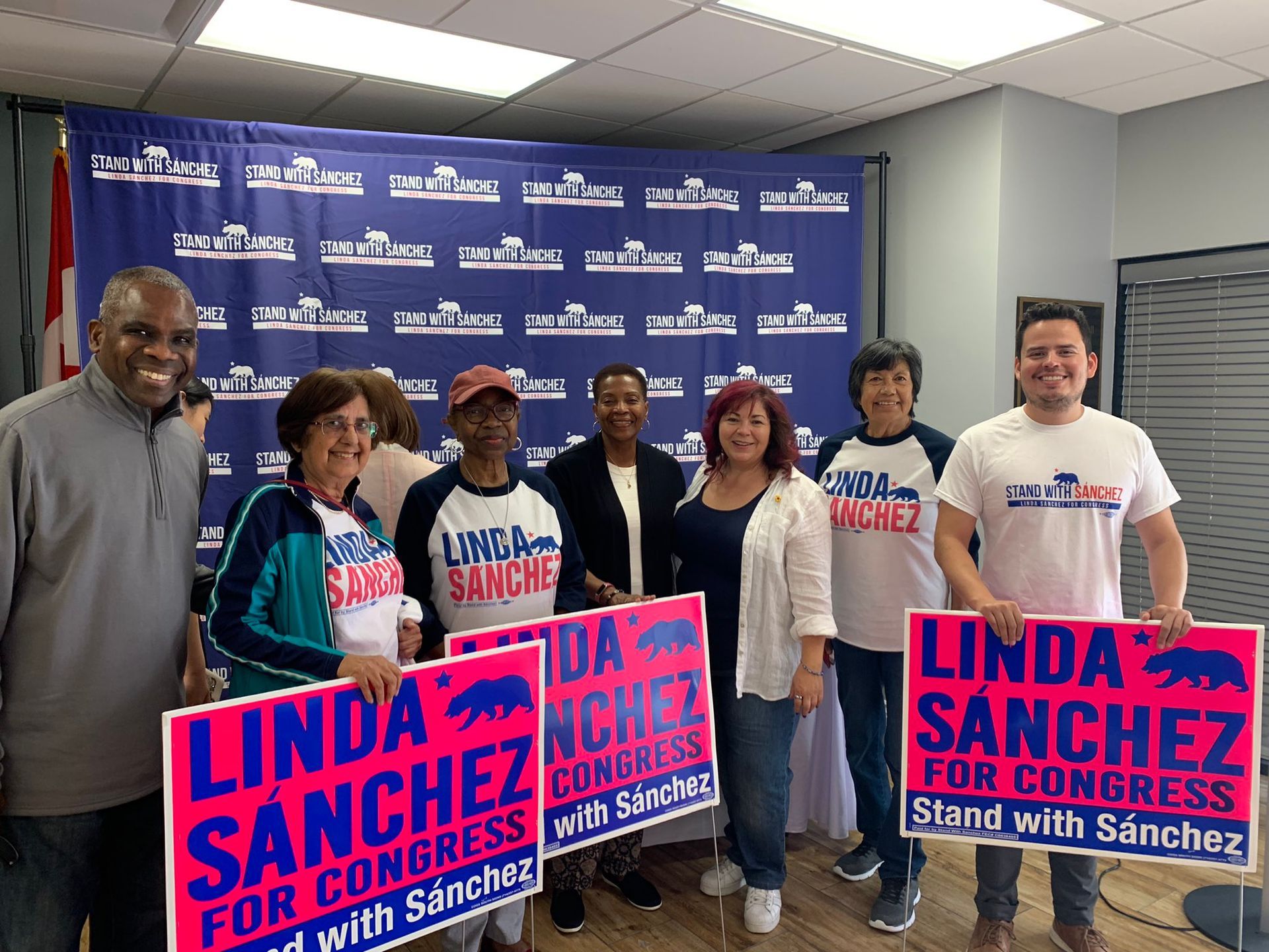 A group of people standing next to each other holding signs for linda sanchez for congress.