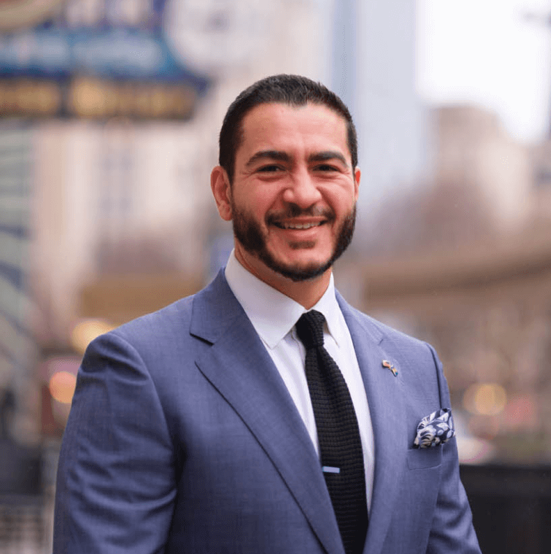 A man in a blue suit is smiling at the camera.