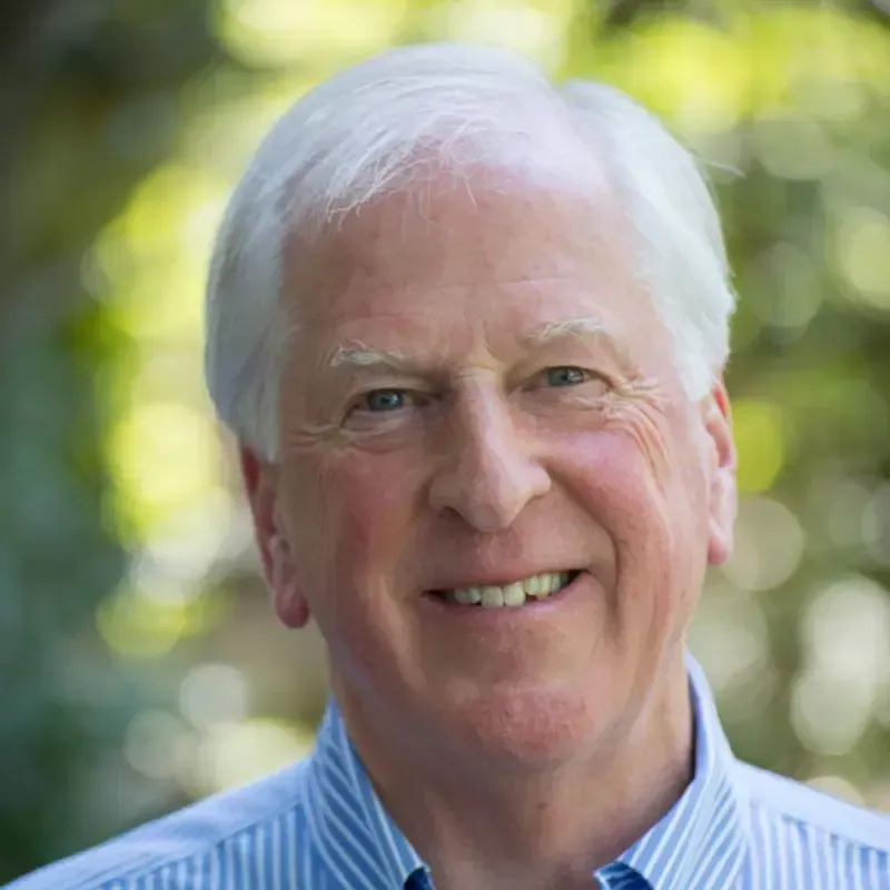 Man in a blue button down is smiling at the camera.