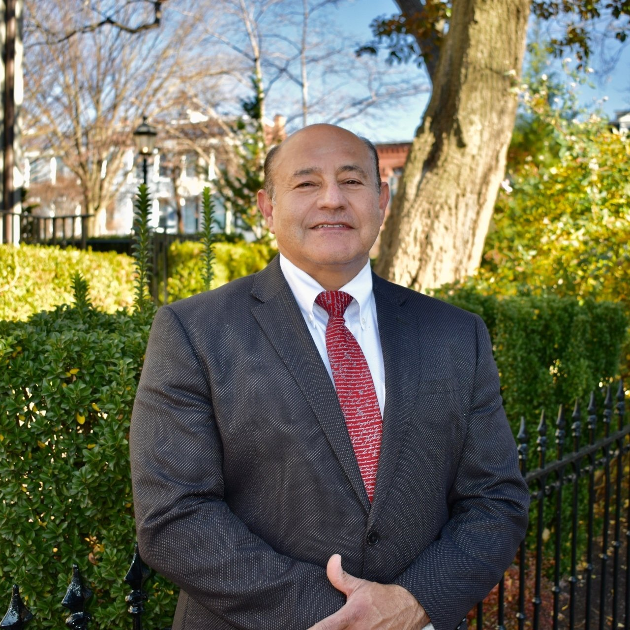 A man in a suit and tie is standing in front of a tree
