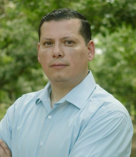 A man in a blue shirt is standing with his arms crossed