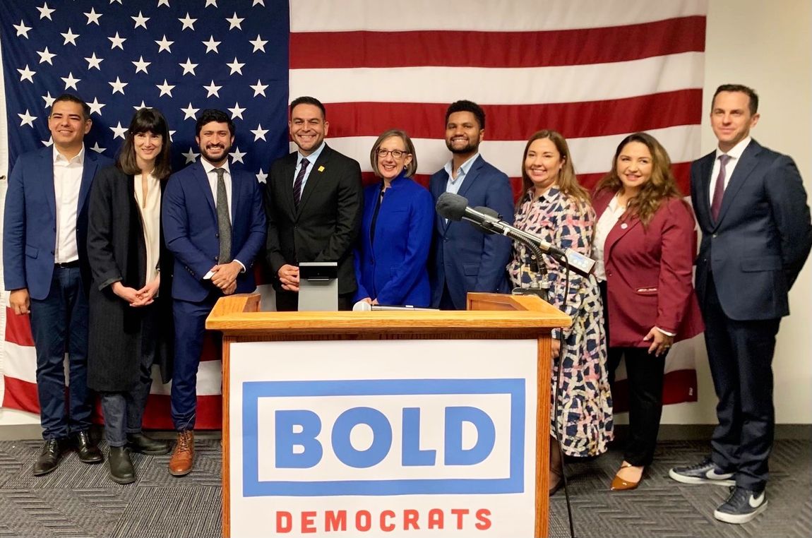 A group of people standing around a podium with the word bold on it.