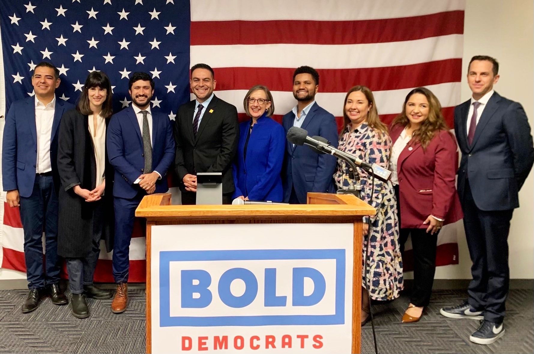 A group of people standing around a podium with the word bold on it.