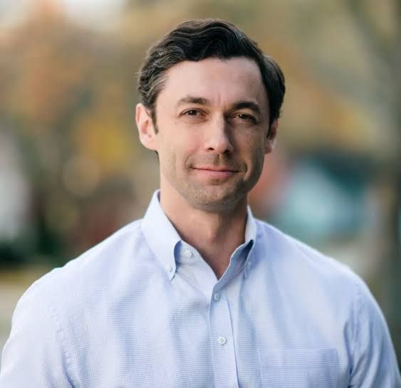 A man in a blue button down is smiling at the camera.