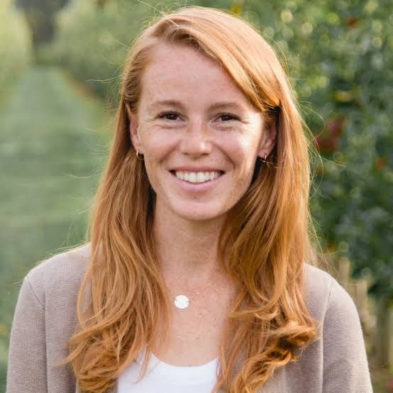 Woman in a brown cardigan is smiling at the camera.