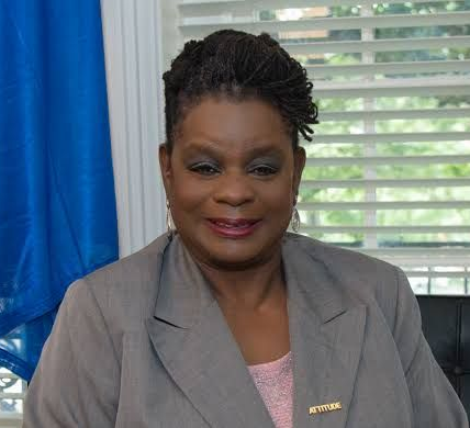 Woman in a gray suit is smiling at the camera.