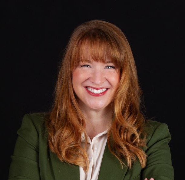 Woman in a green suit is smiling at the camera.