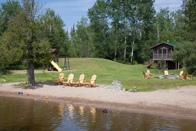 A beach with chairs and a house in the background