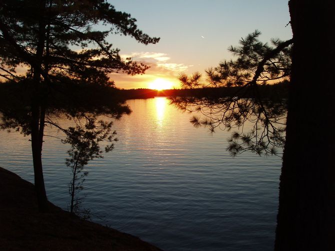 A sunset over a lake with trees in the foreground