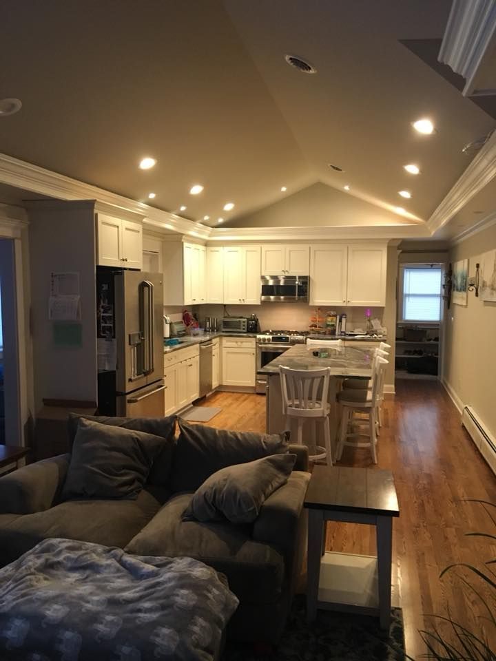 Cozy, open-plan kitchen and living area with white cabinets, stainless steel appliances, and a gray sofa.