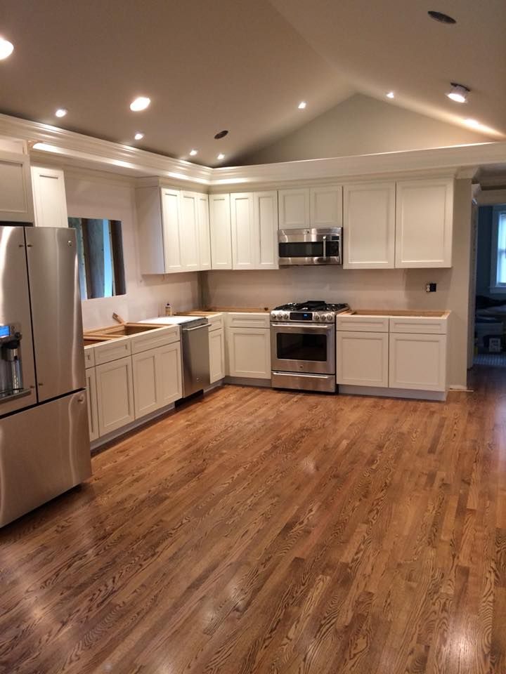Newly renovated kitchen with white cabinets, stainless steel appliances, and wood flooring.
