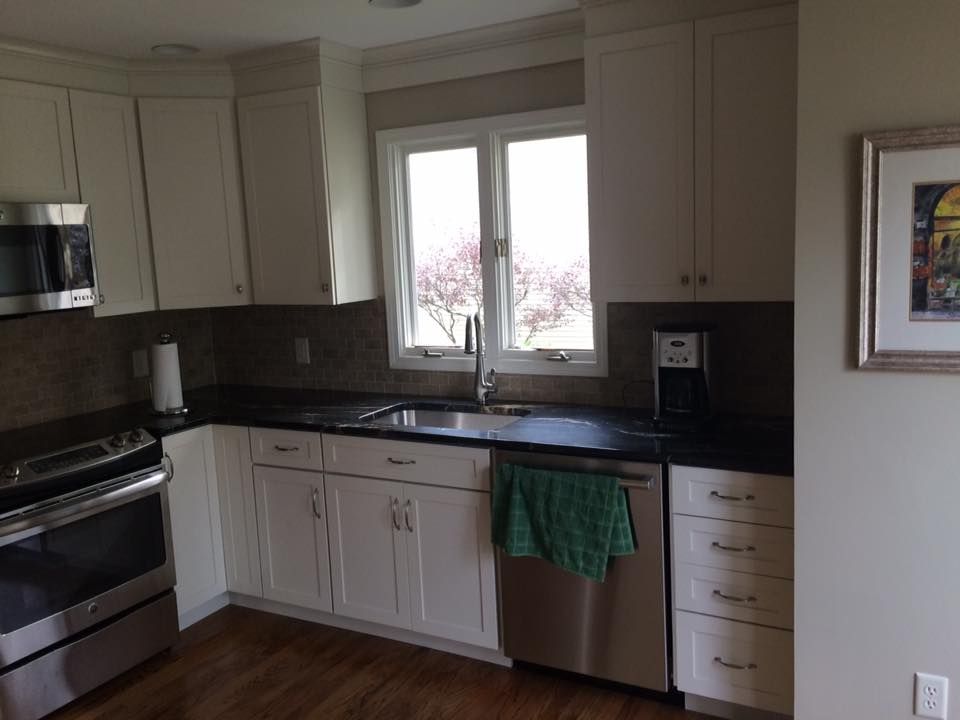 A kitchen with white cabinets, stainless steel appliances, and a window with a view.
