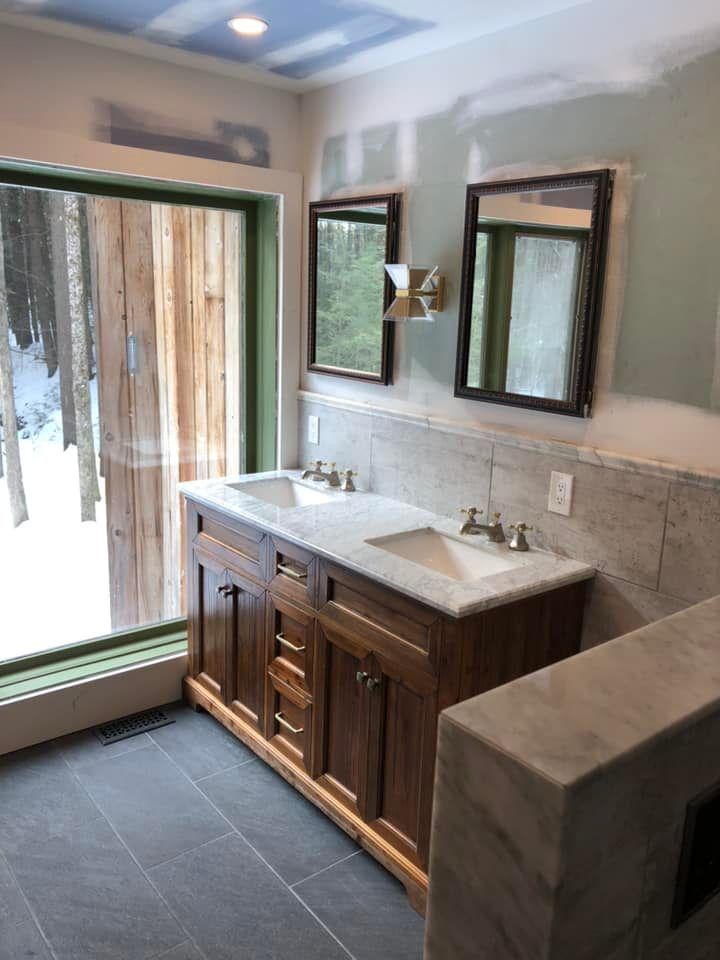 Bathroom with a wooden vanity, two mirrors, and a large window looking outside.