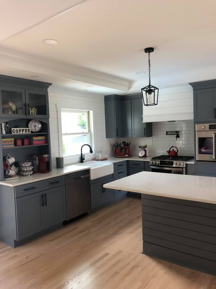 Gray kitchen with white countertops and light wood floors.