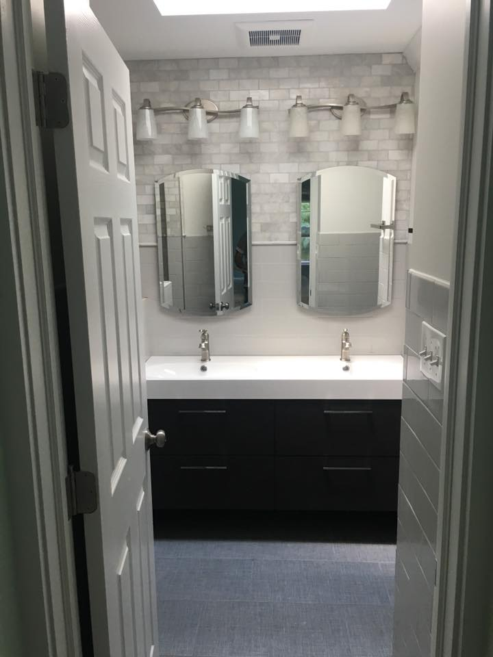 Bathroom with a double vanity. Black cabinet, white countertop, and two mirrors.