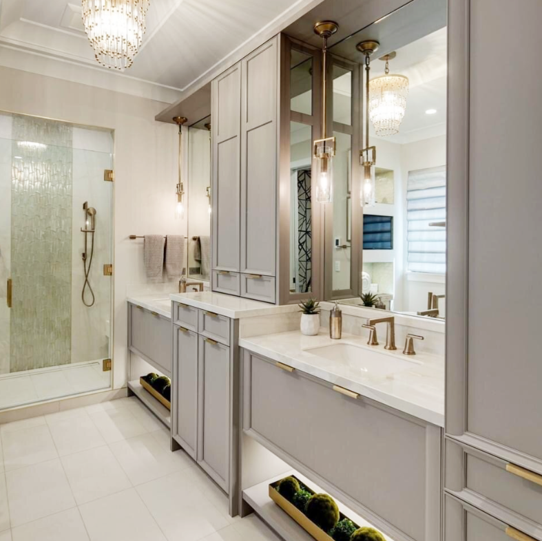 Elegant gray and white bathroom with a shower, vanity, and crystal chandelier.