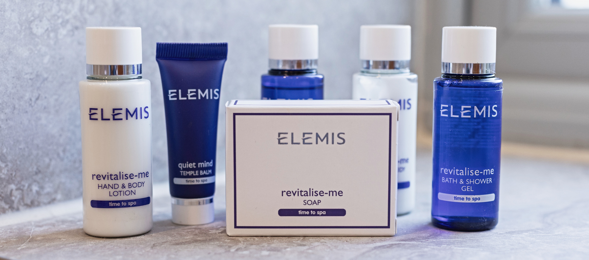 ELEMIS skincare set with lotion, cream, and serum bottles plus a boxed product on a light background