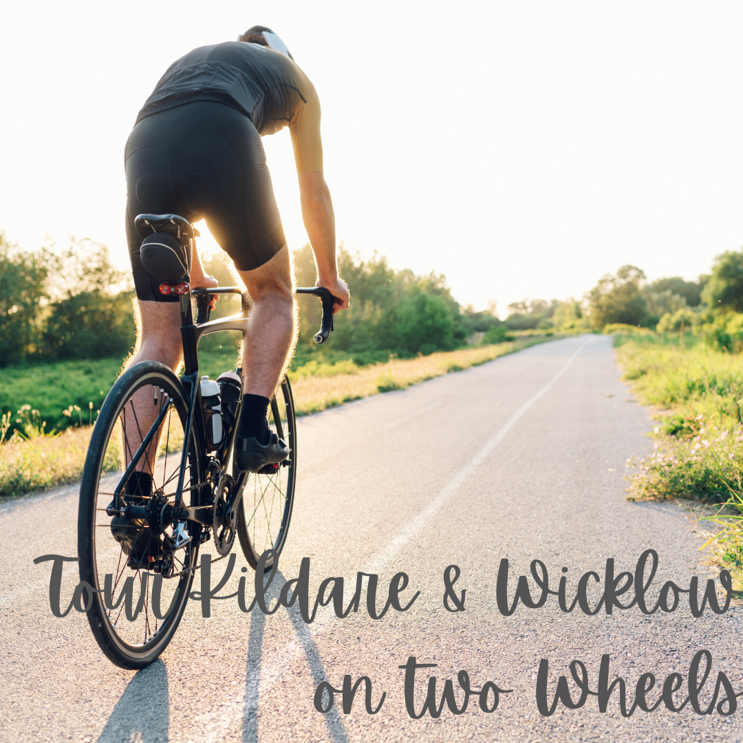 A man is riding a bike down a road with the words tour kildare & wicklow on two wheels below him