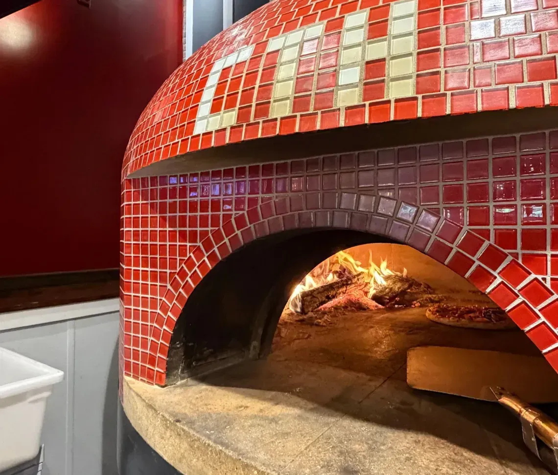 A large, red tiled brick oven with 'CTH' written on it.
