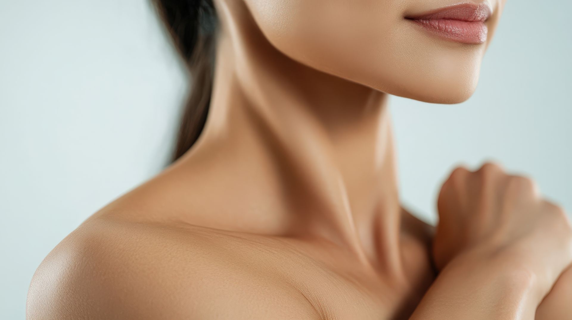 Close-up of a person’s shoulder and face, hand resting on the shoulder against a light background