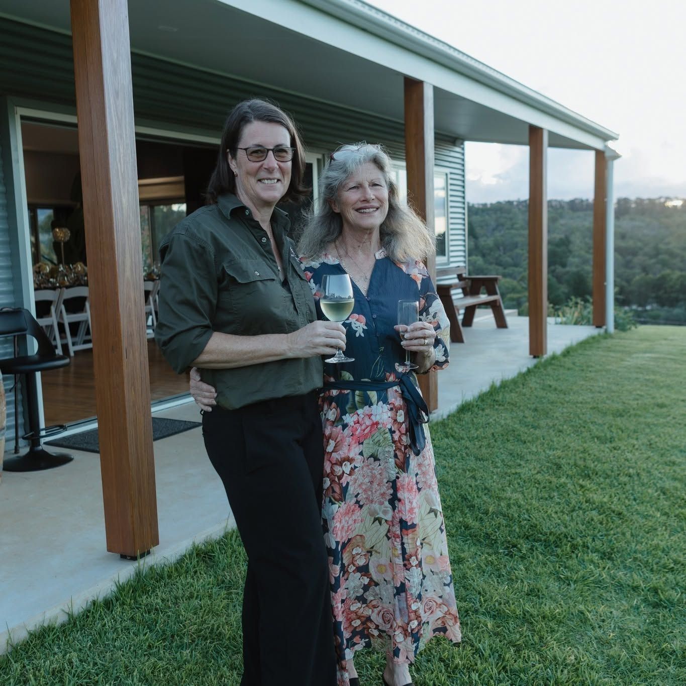 Two Women Holding Drinks and Smiling on a Covered Patio at Sunset — Lakeview Luxury Retreat in Canobolas, NSW