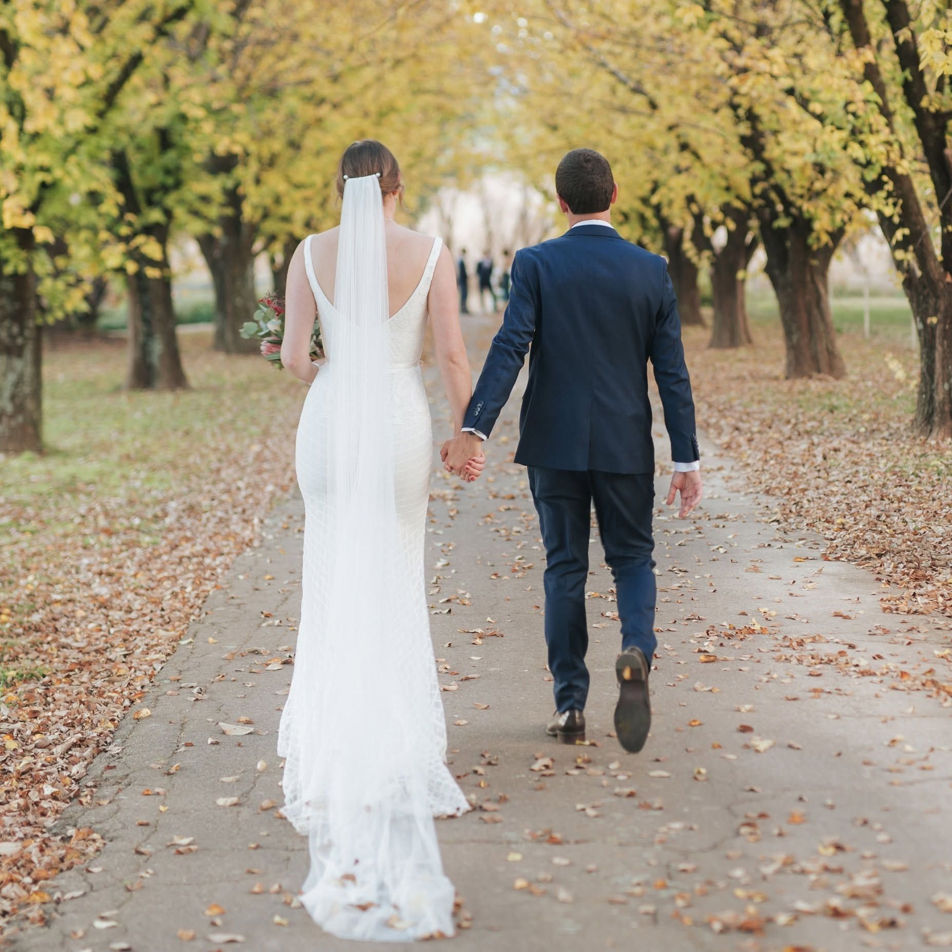 Bride and Groom Walking Hand in Hand Down a Tree-lined Autumn Path — Lakeview Luxury Retreat in Canobolas, NSW
