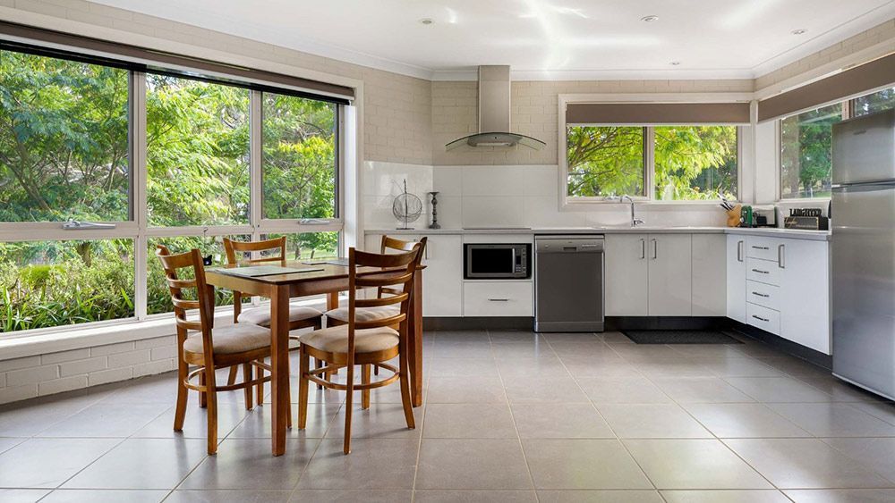 A Kitchen With a Table and Chairs in It and a Lot of Windows — Lakeview Luxury Retreat in Canobolas, NSW