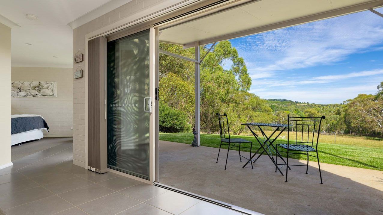 A Patio With a Table and Chairs is Visible Through a Sliding Glass Door — Lakeview Luxury Retreat in Canobolas, NSW
