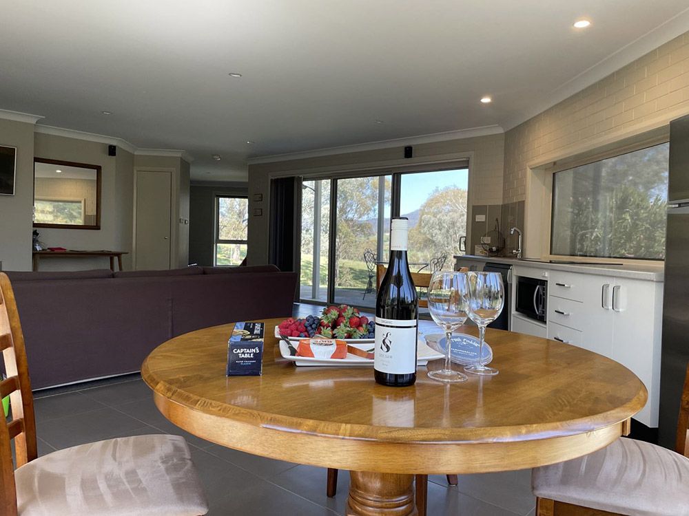 A Bottle of Wine is Sitting on a Wooden Table in a Living Room — Lakeview Luxury Retreat in Canobolas, NSW