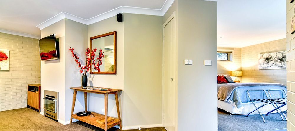 A Bedroom With a Table, Mirror, Television and a Bed — Lakeview Luxury Retreat in Canobolas, NSW