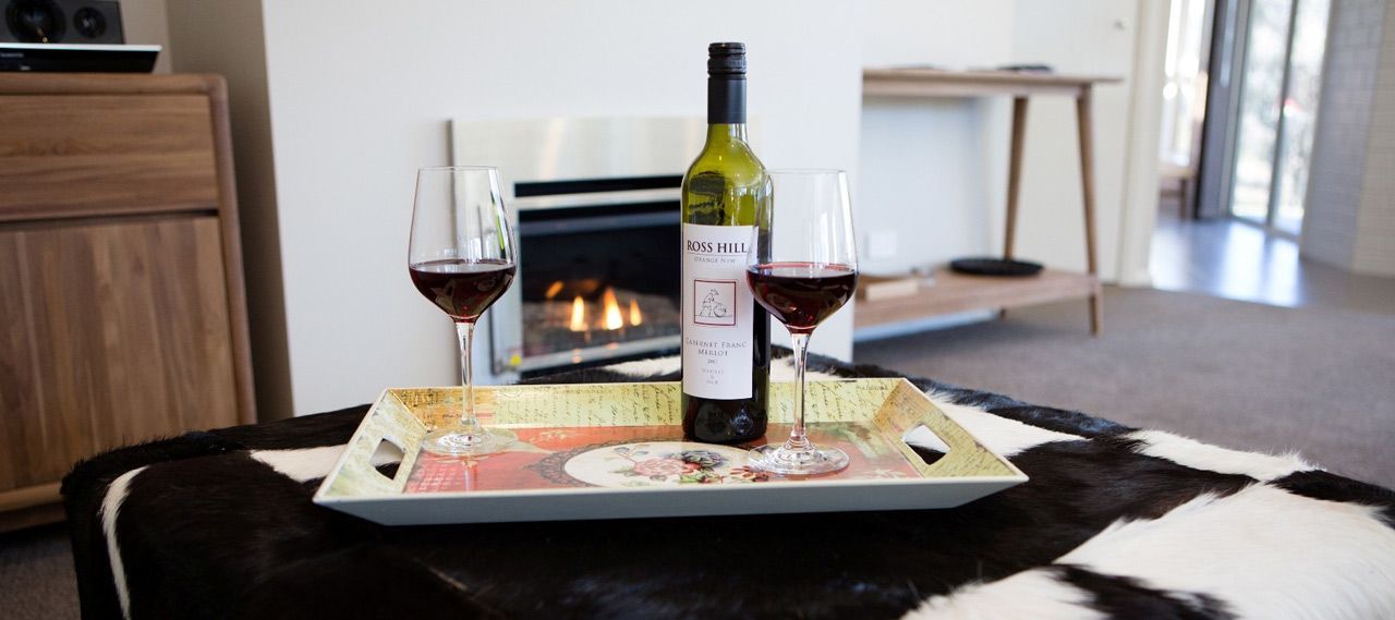 A Bottle of Wine and Two Glasses of Wine Are on a Tray on a Table — Lakeview Luxury Retreat in Canobolas, NSW