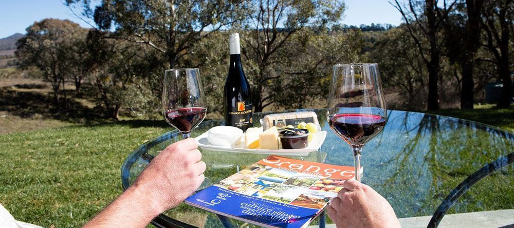 A Person is Sitting at a Table With Two Glasses of Wine and a Magazine — Lakeview Luxury Retreat in Canobolas, NSW