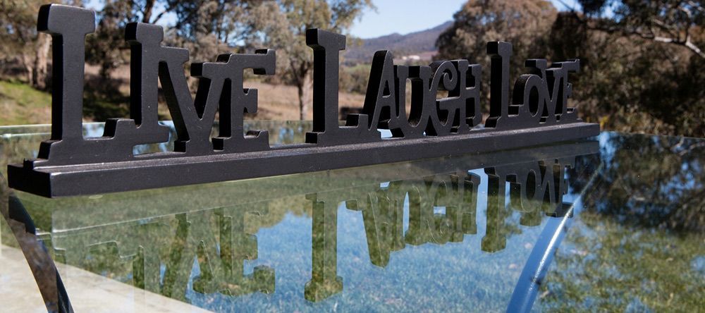 A Sign That Says Live Laugh Love is Reflected in a Pool of Water — Lakeview Luxury Retreat in Canobolas, NSW
