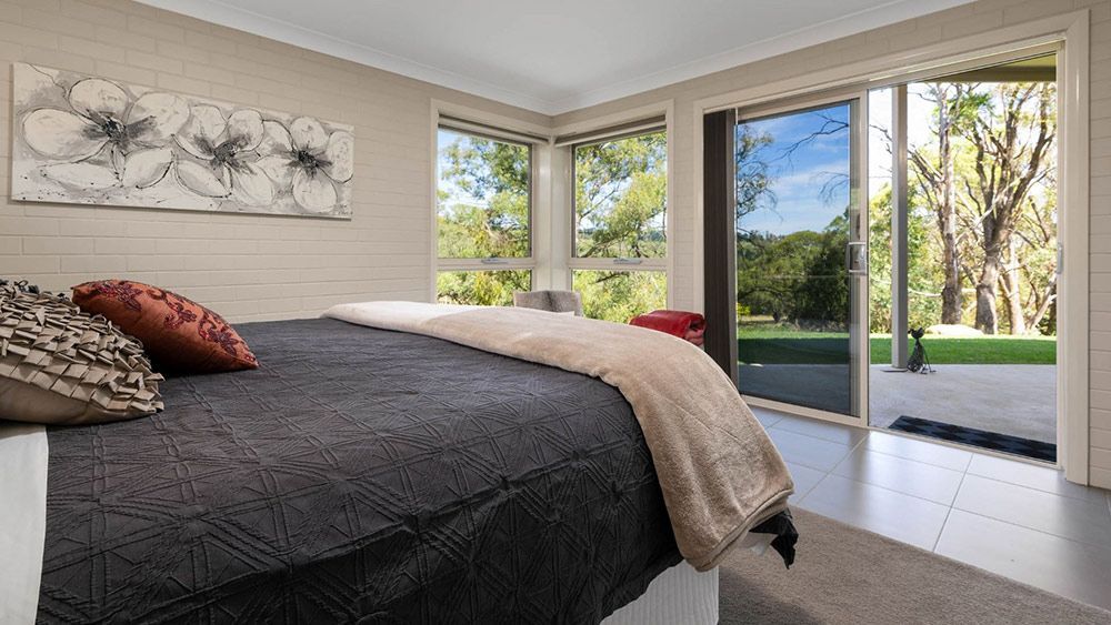A Bedroom With a Large Bed and a Sliding Glass Door Leading to a Patio — Lakeview Luxury Retreat in Canobolas, NSW