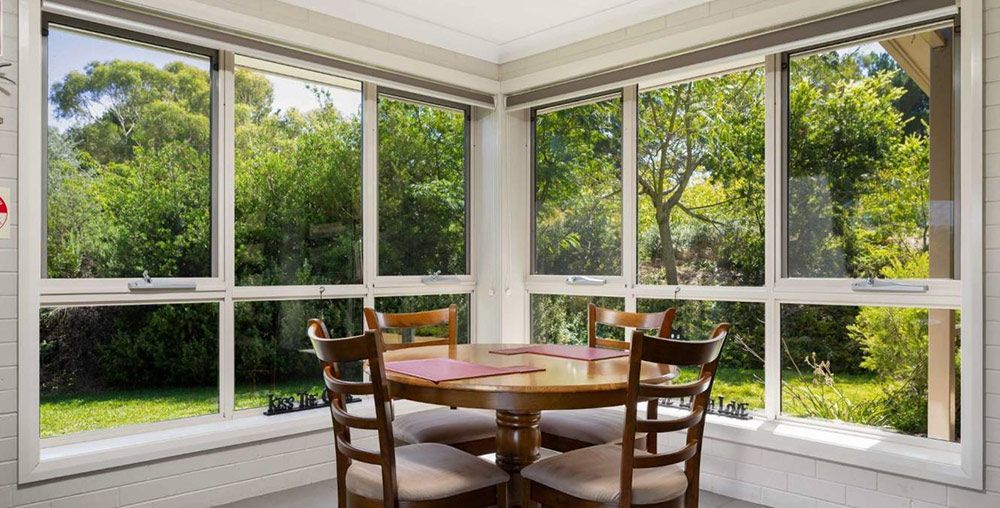 A Dining Room With a Table and Chairs and Lots of Windows — Lakeview Luxury Retreat in Canobolas, NSW