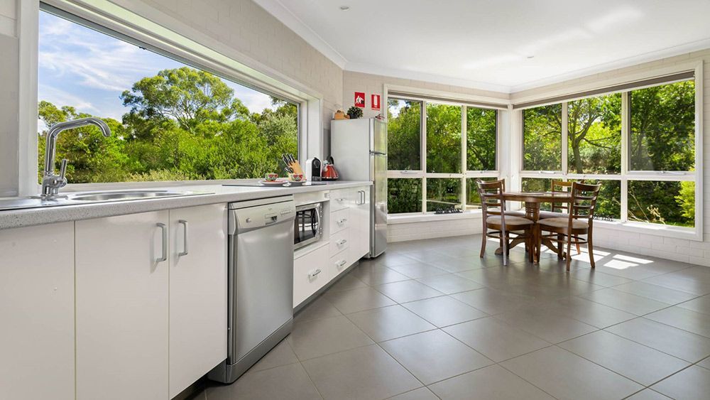 A Kitchen With a Table and Chairs and a Large Window — Lakeview Luxury Retreat in Canobolas, NSW