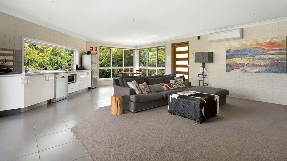 A Living Room With a Couch, Coffee Table, and a Painting on the Wall — Lakeview Luxury Retreat in Canobolas, NSW