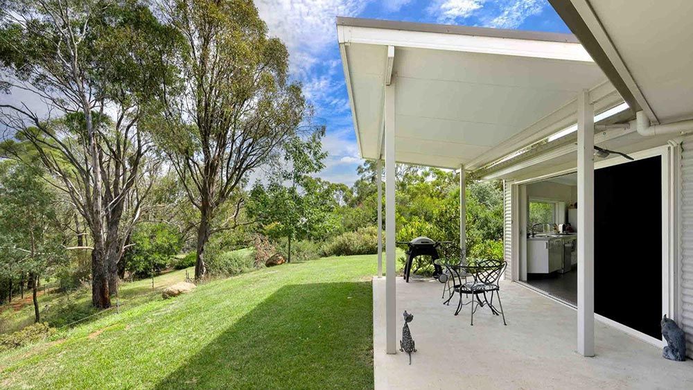 There is a Porch With a Table and Chairs on It — Lakeview Luxury Retreat in Canobolas, NSW