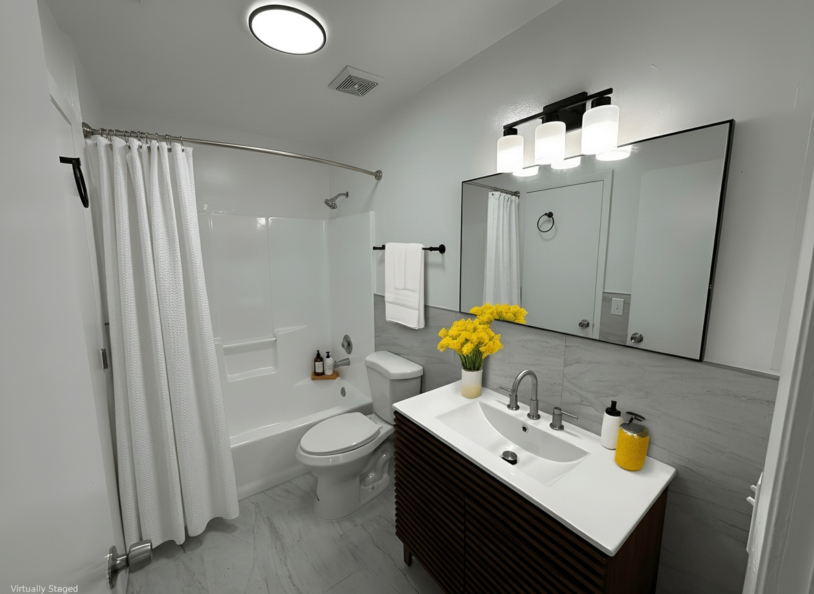 Bathroom with white bathtub, toilet, and vanity; gray tiled floor and walls.