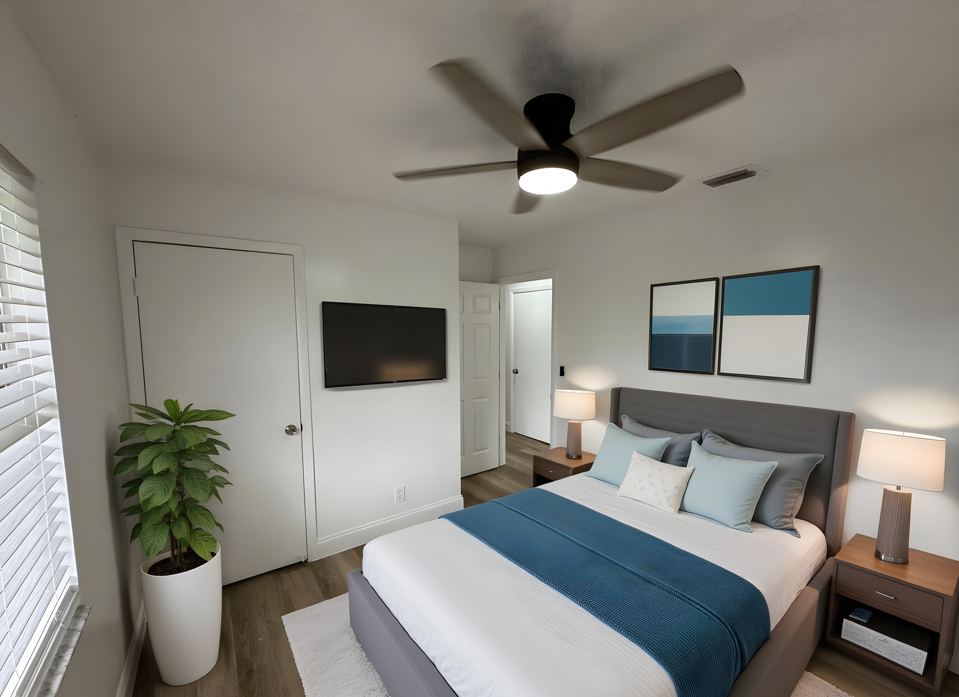 Bedroom with bed, TV, ceiling fan, artwork, and a potted plant.